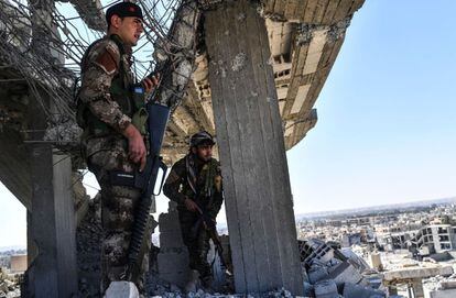 “Hemos tomado el 100% de la ciudad de Raqa pero nuestros hombres están realizando las últimas operaciones de limpieza de desminado y localizando a posibles terroristas escondidos”, afirma por teléfono Talal Silo, portavoz de las FSD. En la imagen, dos miembros de las Fuerzas Sirias Democráticas vigilan en los restos de un edificio en Raqa.