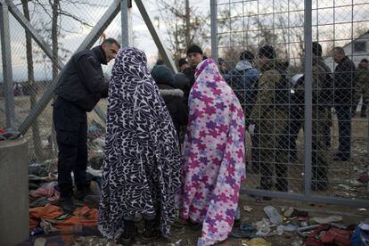 Mujeres con mantas para soportar el frío esperan en la frontera griega para cruzar a Macedonia.