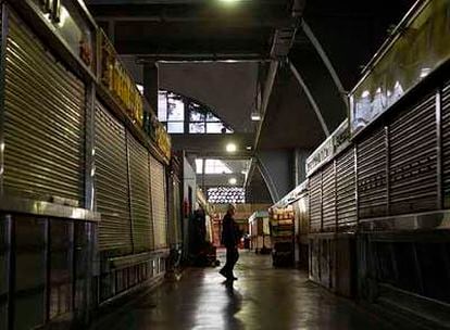 Un hombre camina entre los puestos cerrados del mercado de La Cebada, en pleno horario comercial.