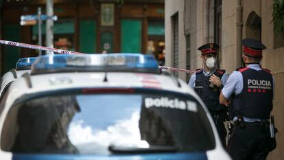 Dos agentes de los Mossos d'Esquadra, junto a un coche-patrulla.