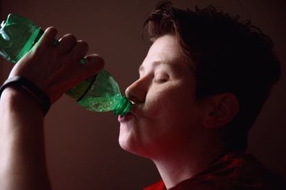 Un adolescente bebe de una botella.