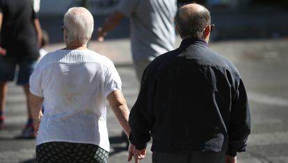 Una pareja de ancianos caminan de la mano en una calle de Madrid.