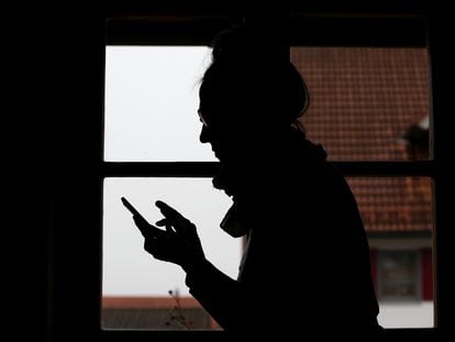 Una mujer usa su teléfono móvil en casa.
