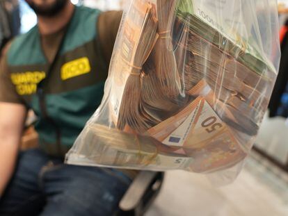 Un agente de la UCO sujeta una bolsa con parte del dinero intervenido este lunes en la Operación Guanxi.