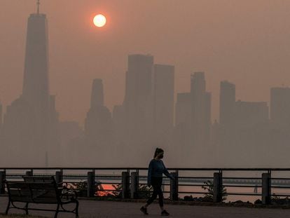 UNa mujer camina con Manhattan al fondo, en Nueva York este jueves.