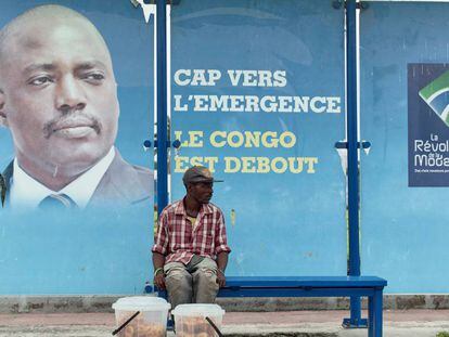 Un vendedor, sentado en una parada de autob&uacute;s con una imagen del presidente Joseph Kabila en Kinshasha, RD Congo. 