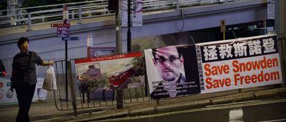 Una mujer espera para cruzar una calle junto a un cartel desplegado en apoyo a Edward Snowden en Hong Kong. 