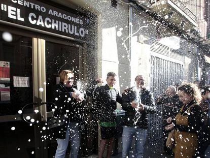 Un grupo de personas celebra haber sido agraciados con el número 26590 el Gordo de Navidad, en el centro aragonés El Chachirulo.