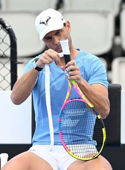 Nadal wraps tape around the handle of his racket.