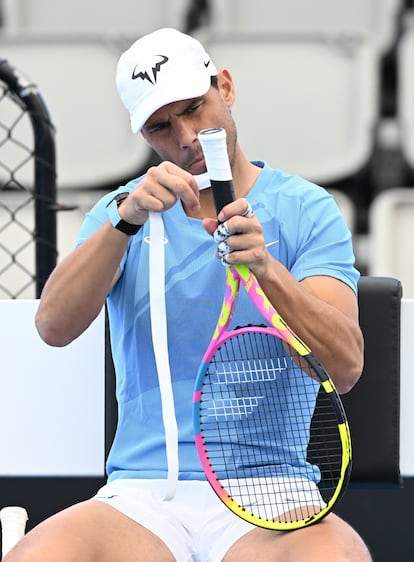 Nadal wraps tape around the handle of his racket.