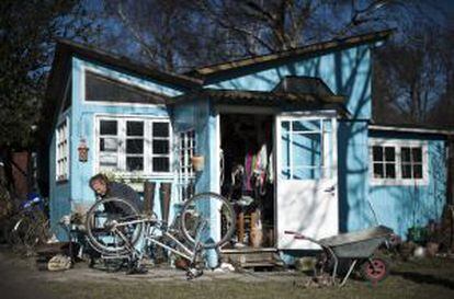 Una mujer repara su bicicleta en la entrada de su casa.