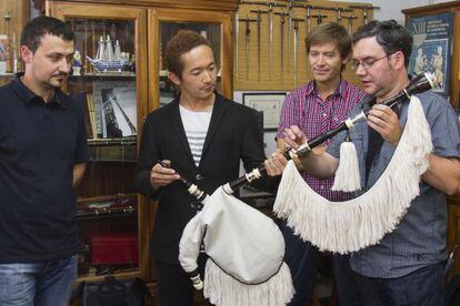 Los hermanos Alfonso (izquierda) y Xosé Gil (derecha) entregan su gaita al japonés Yuki Kojima en presencia del gaiteiro Xosé Manuel Budiño.