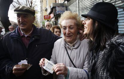 Algunos afortunados con el primer premio de la Lotería del Niño, el 30875, en Alcorcón (Madrid) lo celebran con cava a la puerta de la administración de loterías.