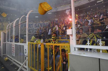 Aficionados del Fenerbahce lanzan sillas al césped al final del partido.