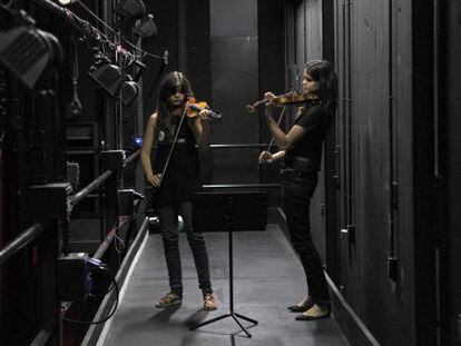 Dos chicas ensayan cn sus violines entre bambalinas, en el Teatro del Canal.