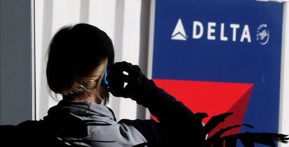 Un passatger parla per telèfon davant un cartell de Delta Airlines, en una imatge d'arxiu.