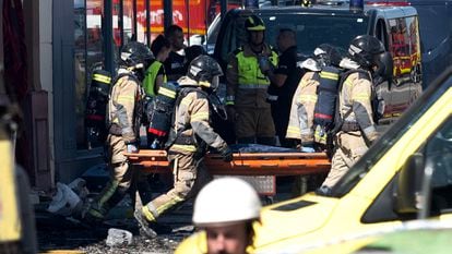 Los bomberos trasladaban el cuerpo de uno de los fallecidos en el incendio, este domingo.