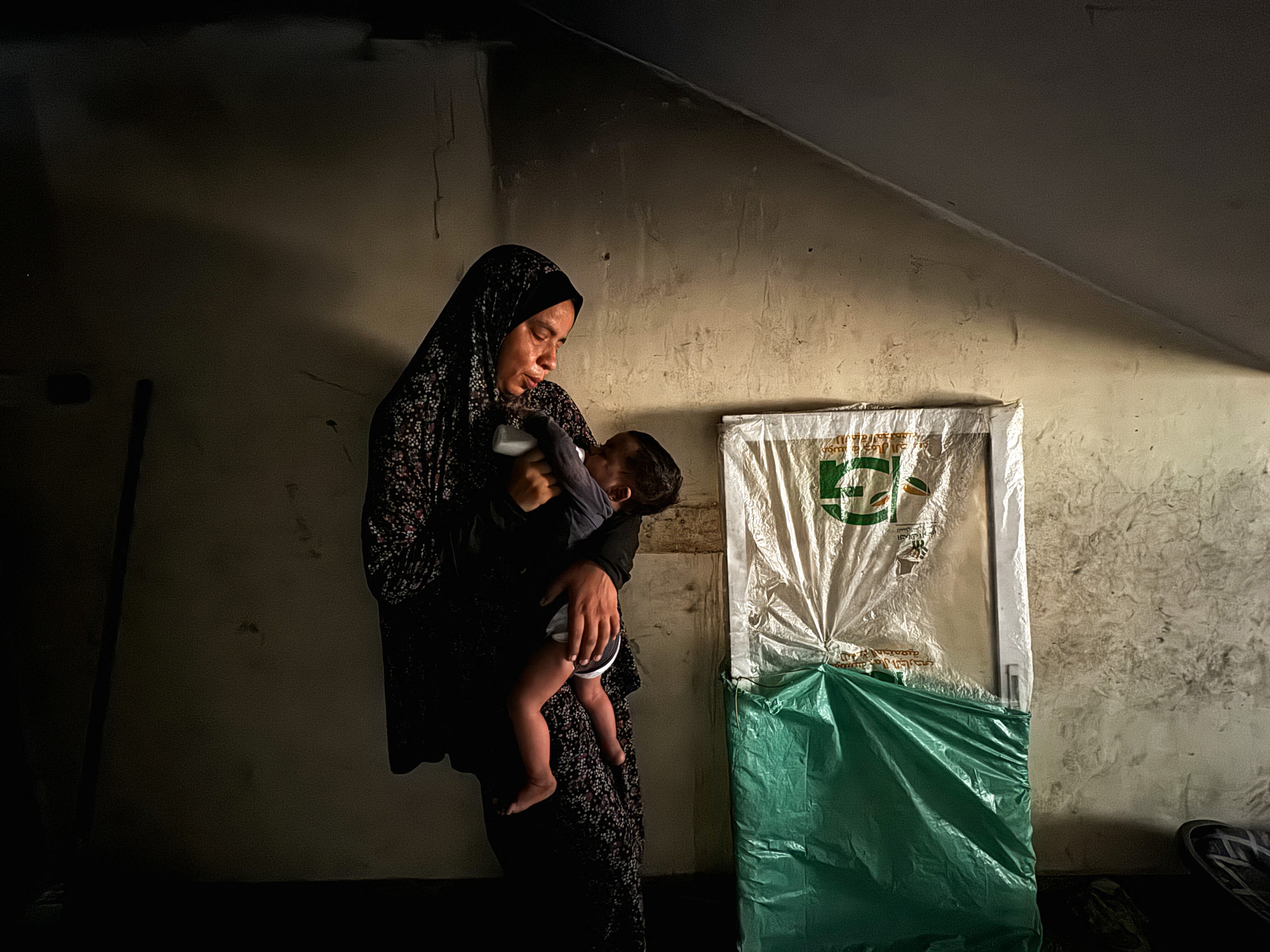 A displaced Palestinian woman helps her son drink milk at a school classroom where she shelters, amid food scarcity, as Israel-Hamas conflict continues, in Khan Younis in the southern Gaza Strip, June 26, 2024. REUTERS/Mohammed Salem