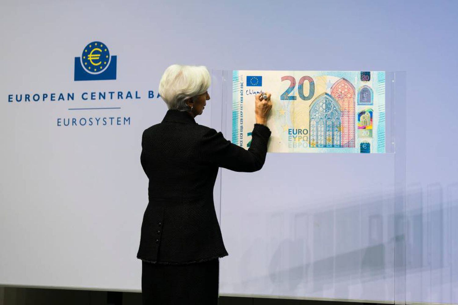 La presidenta del BCE, Christine Lagarde, firma un billete de 20 euros.