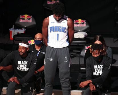 El jugador Jonathan Isaac (de pie en el centro) es el único de los Orlando Magic que no se arrodilla durante el himno ni lleva la camiseta con el lema "Black Lives Matter". En la imagen, antes de jugar contra los Brooklyn Nets en Lake Buena Vista, Florida, el pasado 31 de julio 2020.