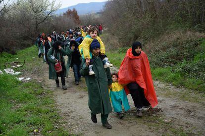Una familia camina bajo la lluvia mientras intenta atravesar Macedonia en su camino hacia el norte de la Unión Europea.