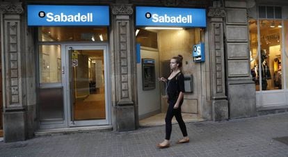 Una dona passa per una oficina de Banc Sabadell, a Barcelona.