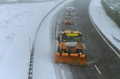 Una máquina quitanieves limpia la A-67 tras una nevada por la que varios camiones permanecen bloqueados, este sábado, en la localidad cántabra de Arenas de Iguña.