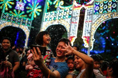 Una niña reacciona mientras posa para un fotografía con sus padres en la instalación de luces navideñas de Spalliera durante la celebración del festival navideño Wonderland en los Jardines de la Bahía de Singapur, el 1 de diciembre de 2017.