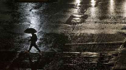 Un hombre camina bajo la lluvia en una calle de Santiago.