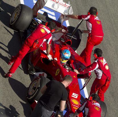 El piloto español Fernando Alonso es remolcado por los mecánicos de Ferrari en el pit- lane.