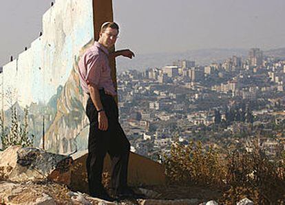 Uri Bank, junto al muro de Gilo, contempla la aldea palestina de Beit Yala. En la otra imagen, Meir Turjeman junto a los sacos terreros que protegen la entrada de una guardería.