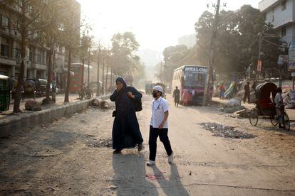 Una mujer y su hijo caminan por las calles de Dacca entre una gran nube de contaminación. 