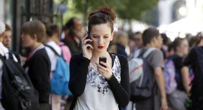Una joven con dos teléfonos móviles en Madrid. 