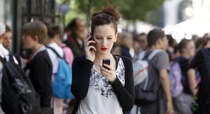 Una joven con dos teléfonos móviles en Madrid.