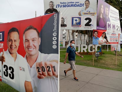 Un hombre camina frente a varios carteles electorales el pasado 15 de marzo en Lima (Perú).