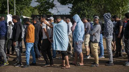 Solicitantes de asilo en el centro holandés de Ter Apel esperan este sábado en una fila.