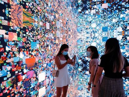 Tres visitantes a la Feria de Arte Digital de Hong Kong junto a una obra inmersiva de Refik Anadol que se convertirá en un certificado digital único (NFT) y se subastará en Sotheby's.