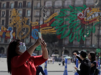 Una mujer toma una fotografía con su teléfono celular frente a la Catedral Metropolitana en el Zócalo de la Ciudad de México