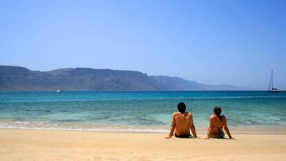 Una pareja sentada en una playa de la isla de La Graciosa (Canarias).