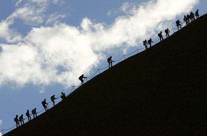 Turistas escalando la cima del Uluru.