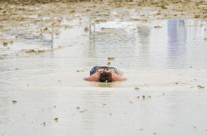 Una mujer permanece tumbada en el barro después de la enorme tromba de agua caída el pasado sábado sobre el desierto en que se celebra el Burning Man. 