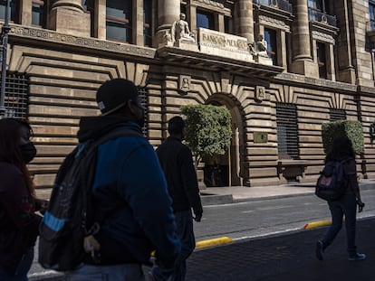 Un grupo de personas camina frente a la sede del Banco de México, en Ciudad de México.