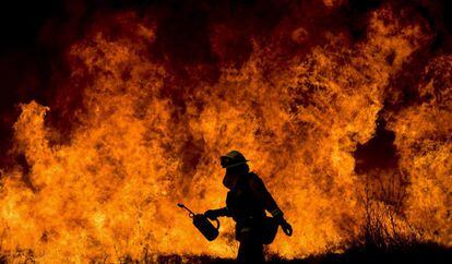 Un bombero del cuerpo del condado de Ventura atiende el incendio 'Thomas' que se ha expandido por 60.000 hectáreas y ha obligados a miles de personas a abandonar sus hogares. 