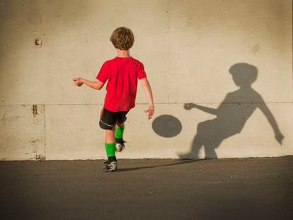 Un niño juega al fútbol solo.