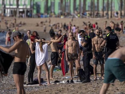 Agentes de la policía piden a los ciudadanos no tumbarse en la playa de la Barceloneta, este miércoles.