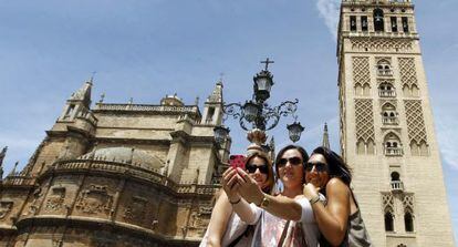 Turistas se fotograf&iacute;an con la Giralda y la Catedral de Sevilla.