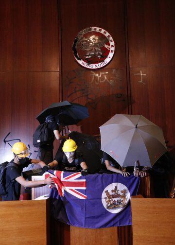 Los manifestantes colocan la bandera colonial de Hong Kong en el atril del Parlamento.