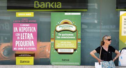 Una mujer, junto a la fachada de una entidad bancaria.
