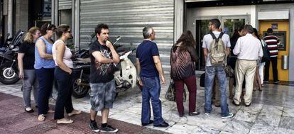 Un grupo de personas hace cola ante un cajero autom&aacute;tico de un banco griego, en Atenas, tras la imposici&oacute;n de un corralito por parte del Gobierno.