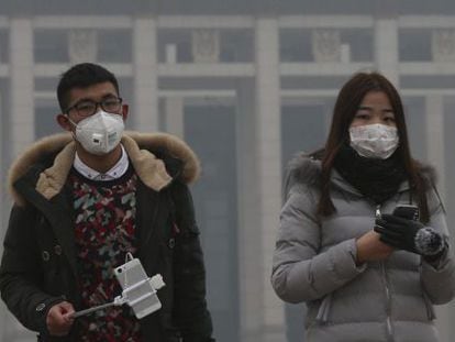 Una pareja usa mascarillas para protegerse de la contaminación ambiental durante una visita a la plaza de Tiananmen en Pekín (China).